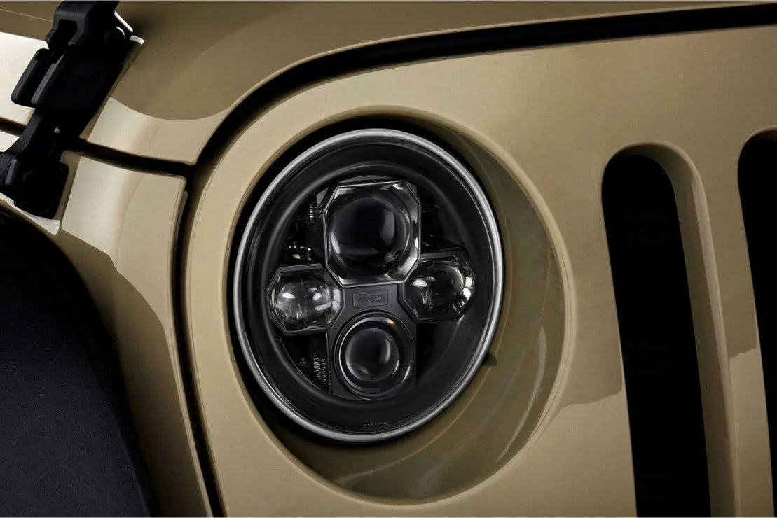 Close-up of a round LED Jeep Wrangler headlight on a tan vehicle, off-road accessory