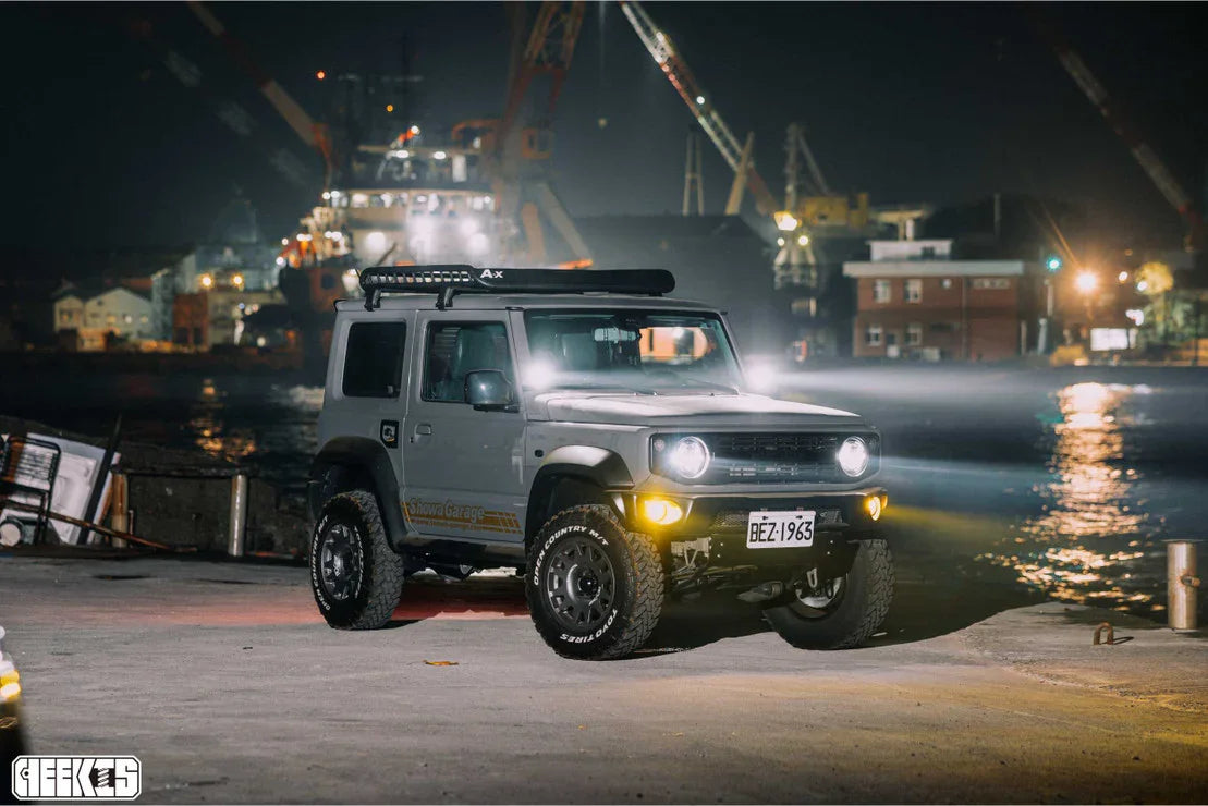 Modified off-road SUV with roof rack and spot lights parked near waterfront at night