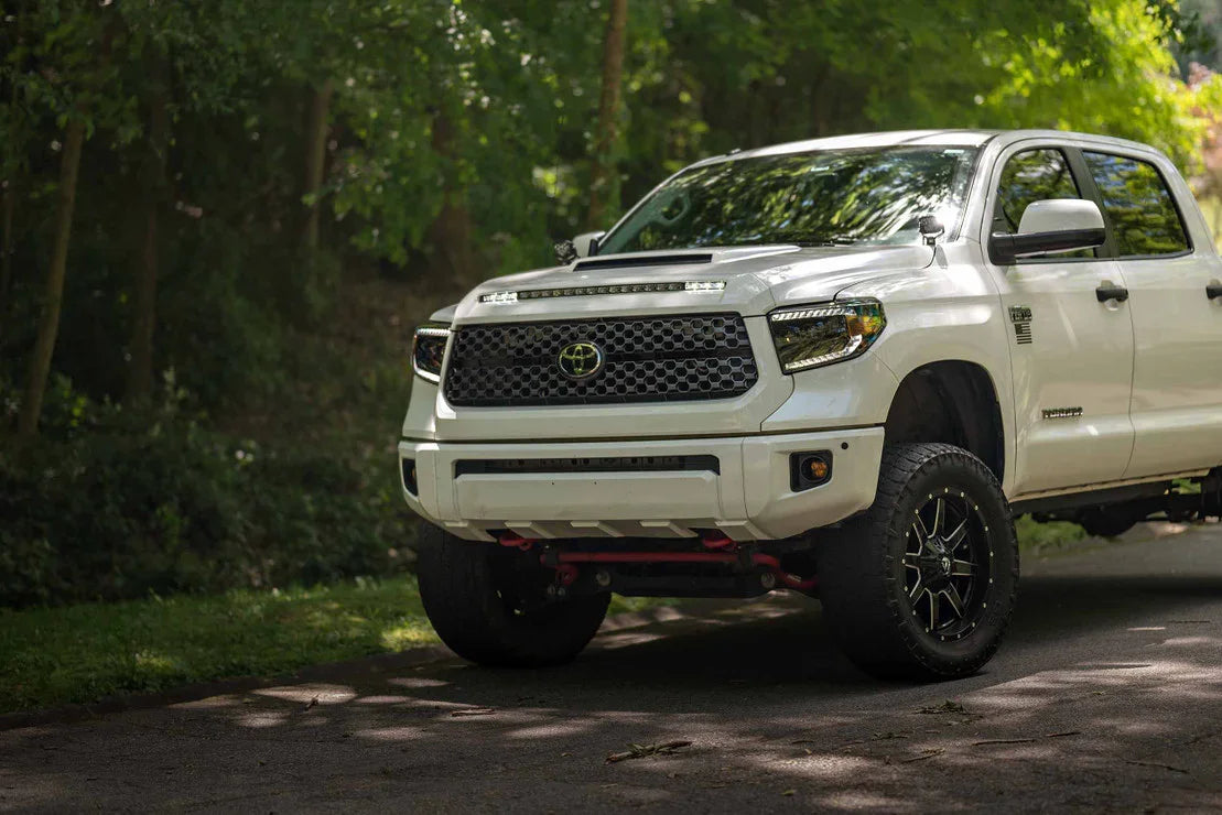 White Toyota Tundra with custom LED headlights and off-road wheels parked outdoors
