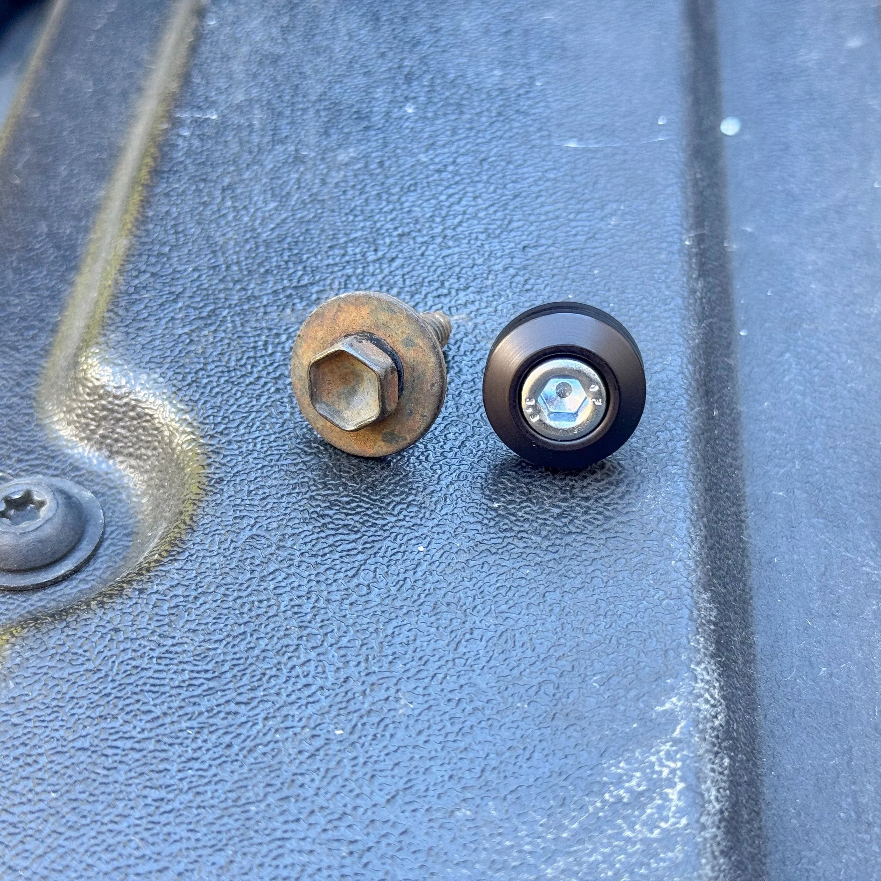 Old and new Tacoma bed bolt hardware on textured truck bed surface