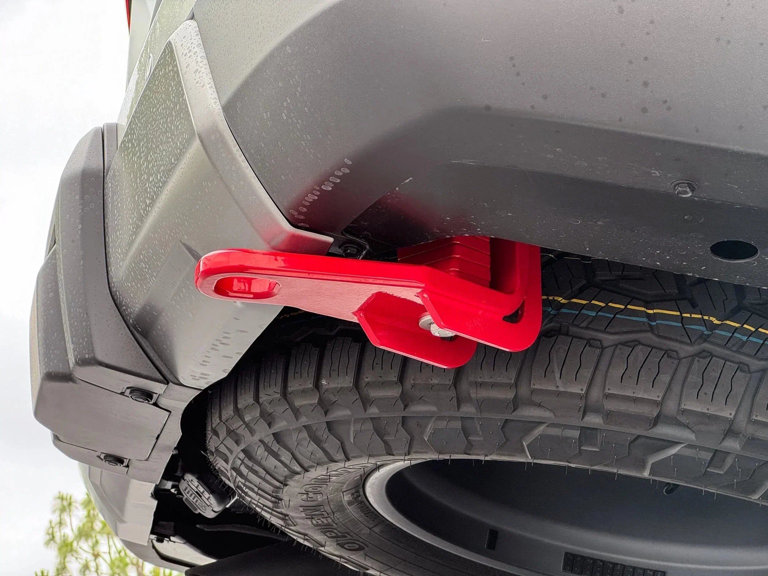 Red rear recovery point mounted to off-road vehicle bumper above spare tire