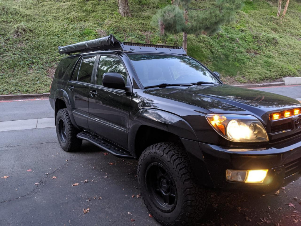 Black Toyota 4Runner with off-road tires and roof-mounted awning parked outdoors