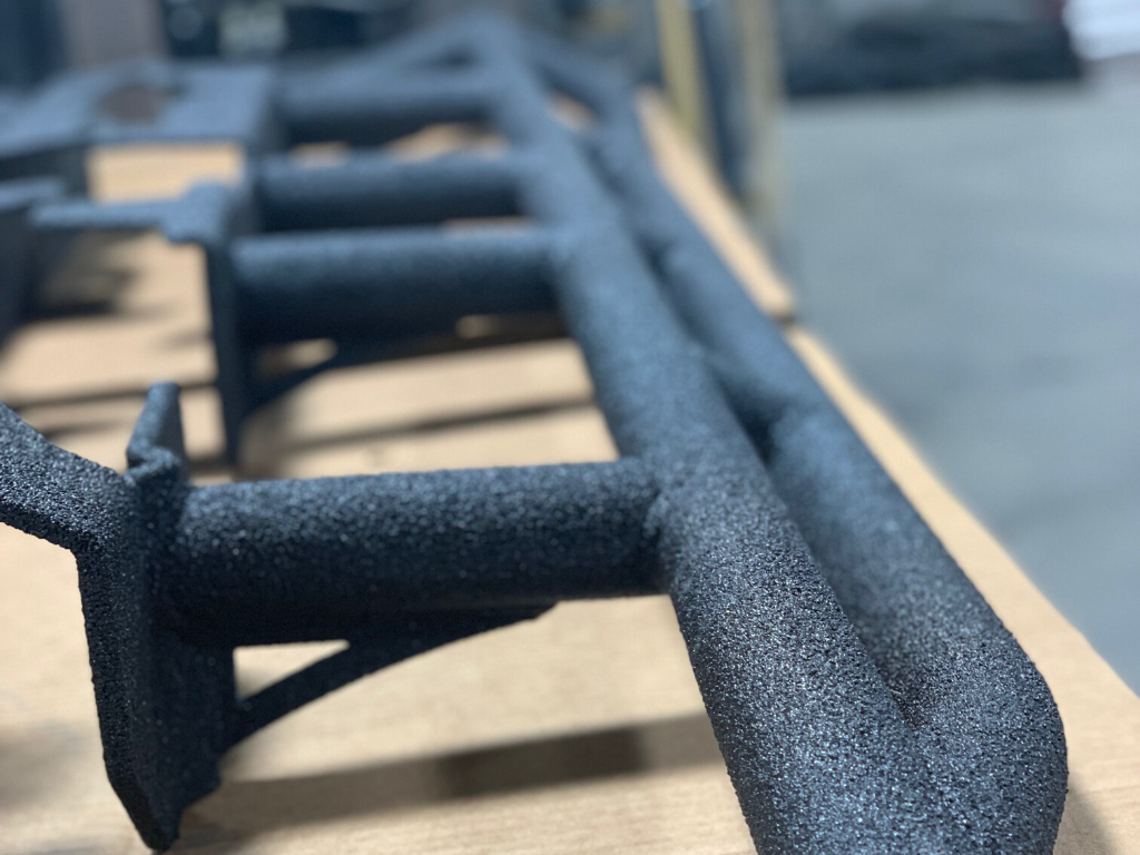 Textured black steel rock slider for off-road vehicle, close-up on workshop table