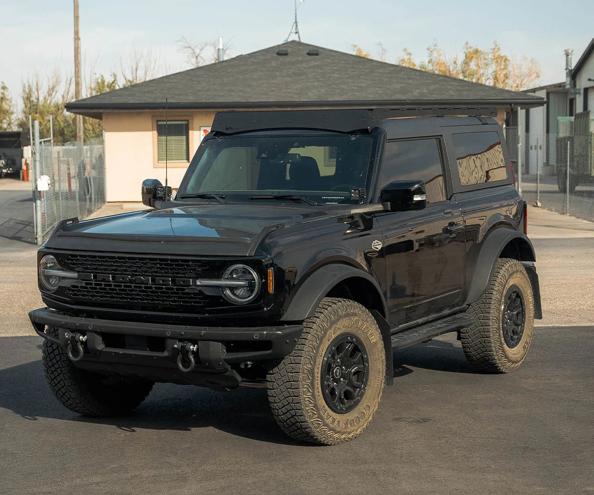Black 2-door Ford Bronco with off-road tires and Prinsu roof rack in parking lot