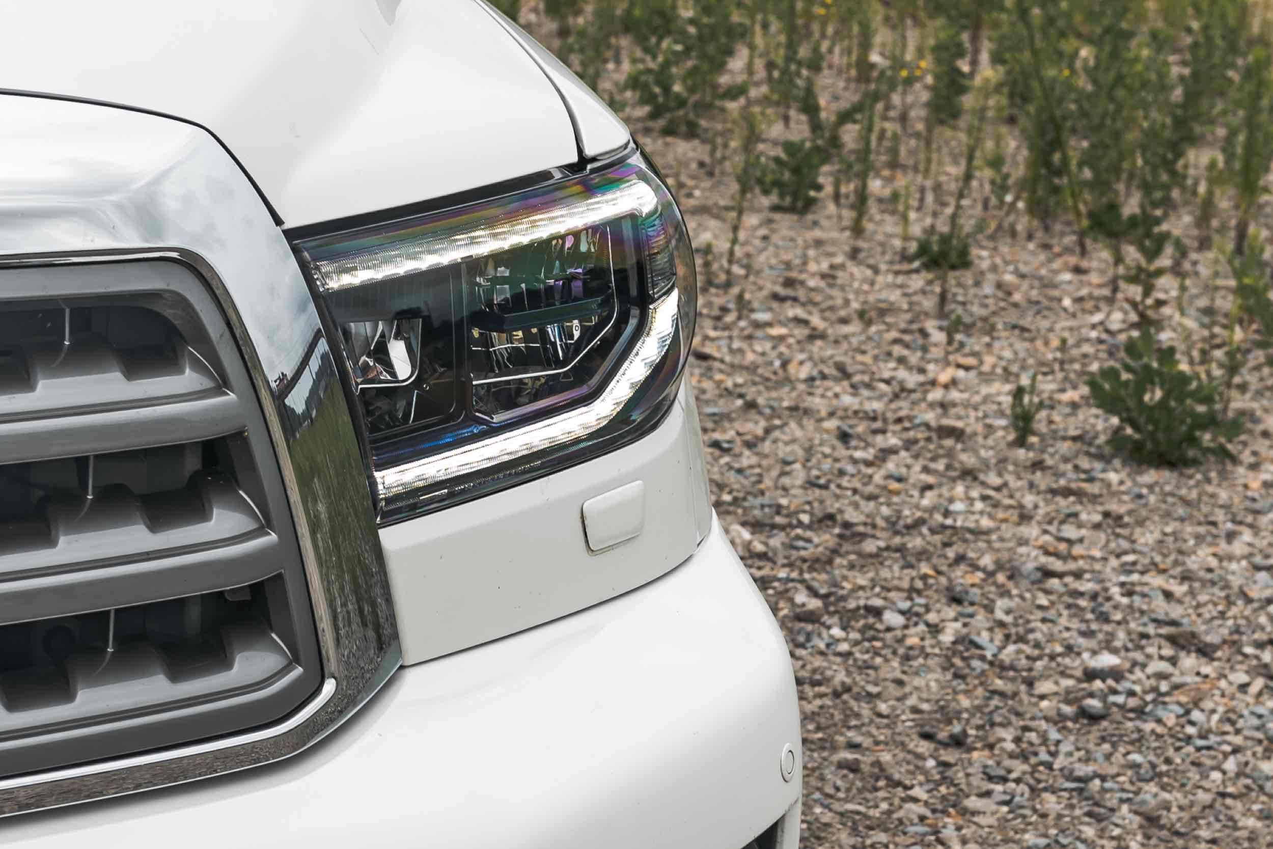 Close-up of LED headlights on a white Toyota Tundra parked outdoors on gravel