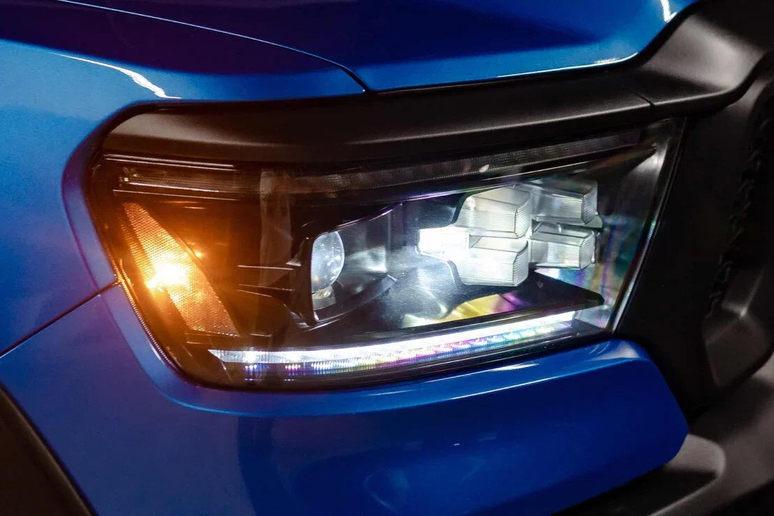 Close-up of blue truck with aftermarket LED headlight and amber turn signal illuminated