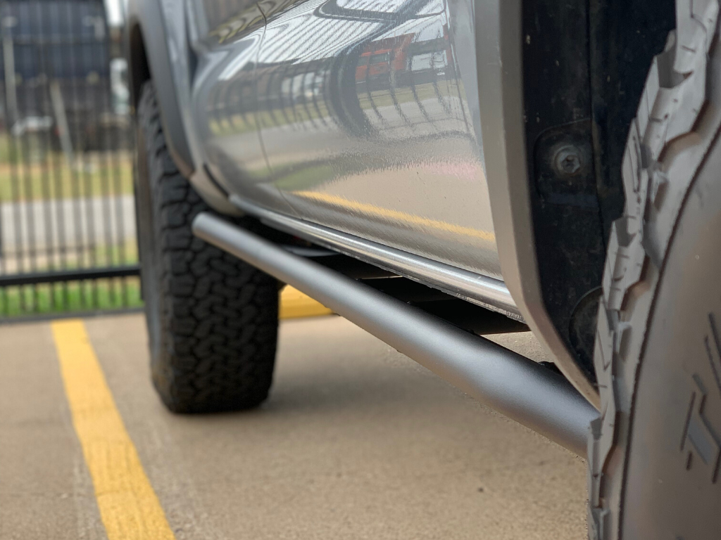 Close-up of vehicle rock sliders and all-terrain tires for overlanding truck