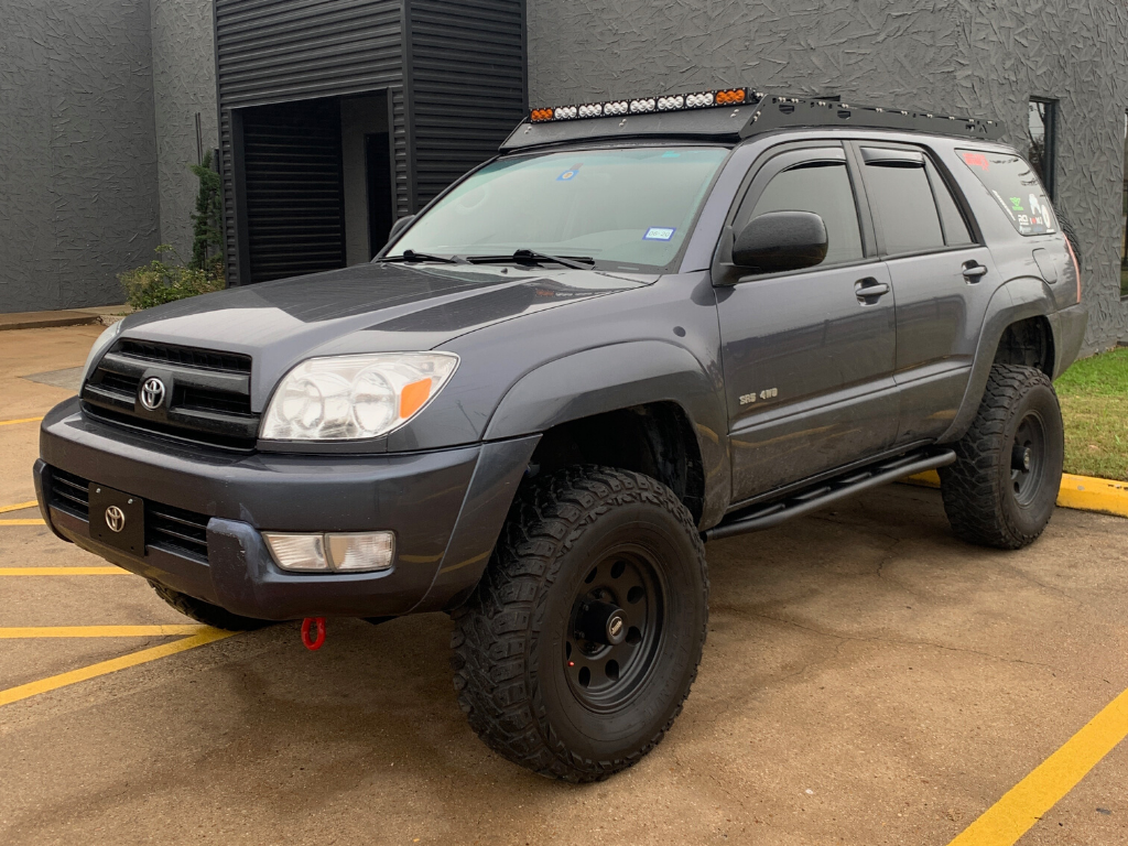 Lifted Toyota 4Runner with off-road tires, roof rack, and LED light bar in parking lot
