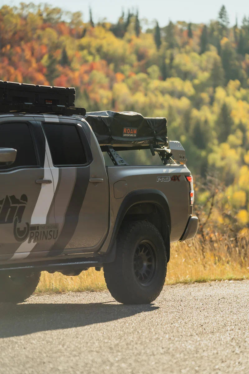 3rd Gen Nissan Frontier bed bars with rooftop tent and gear, overlanding in scenic forest