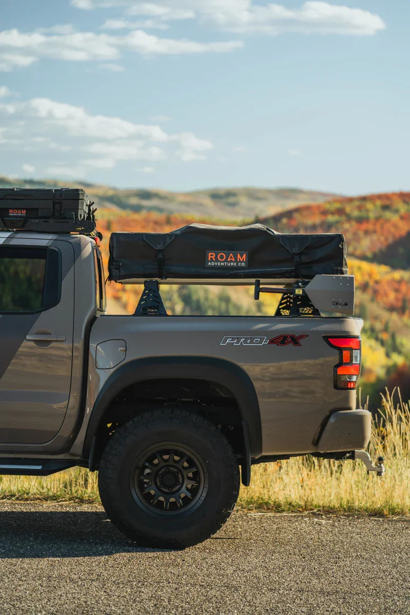 Nissan Frontier PRO-4X with bed bars and ROAM Adventure rooftop tent in outdoor setting