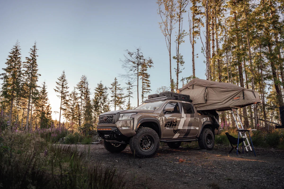 Nissan Frontier equipped with bed bars and rooftop tent at forest campsite