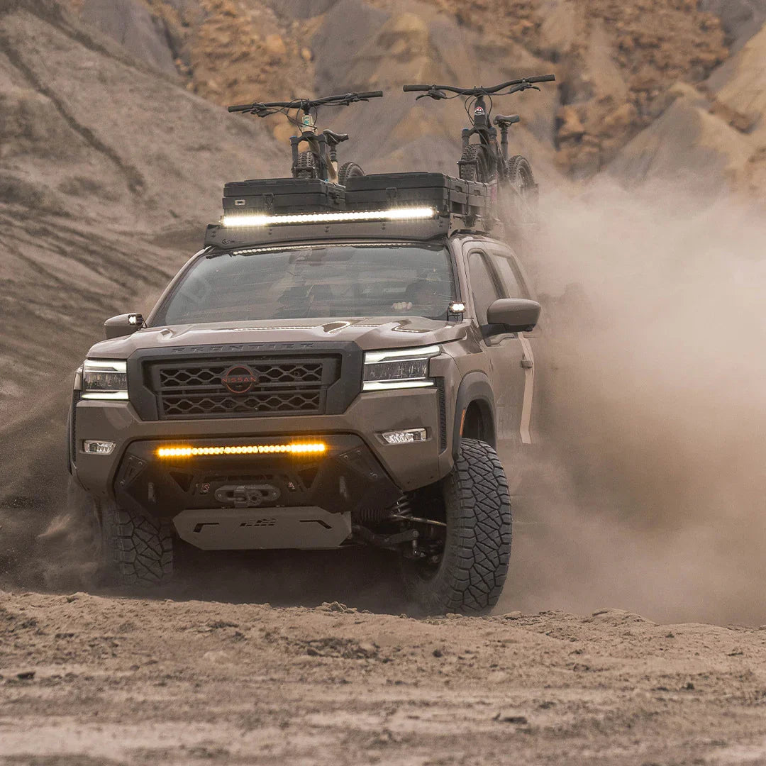 Off-road Nissan Frontier drifting on dirt trail with roof rack and mountain bikes
