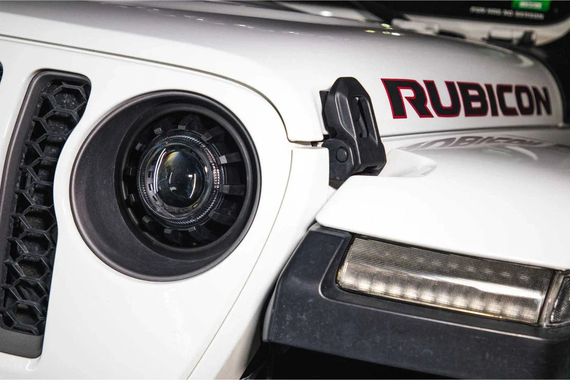 Close-up of a white Jeep Rubicon front headlight, grille, and hood latch
