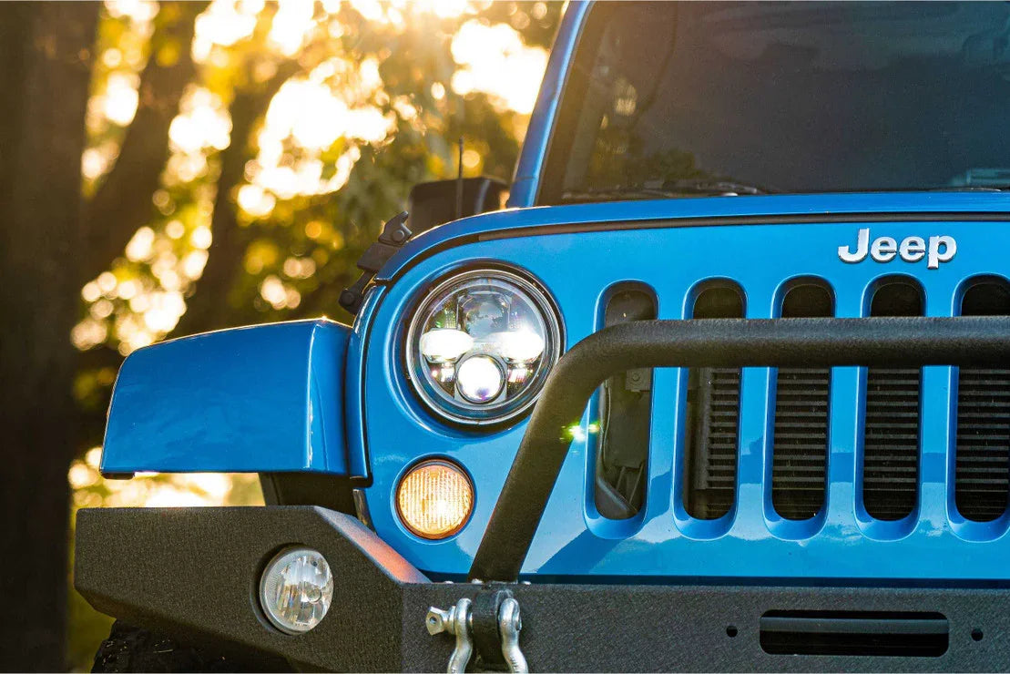 Close-up of blue Jeep Wrangler front grille with aftermarket bumper and LED headlights