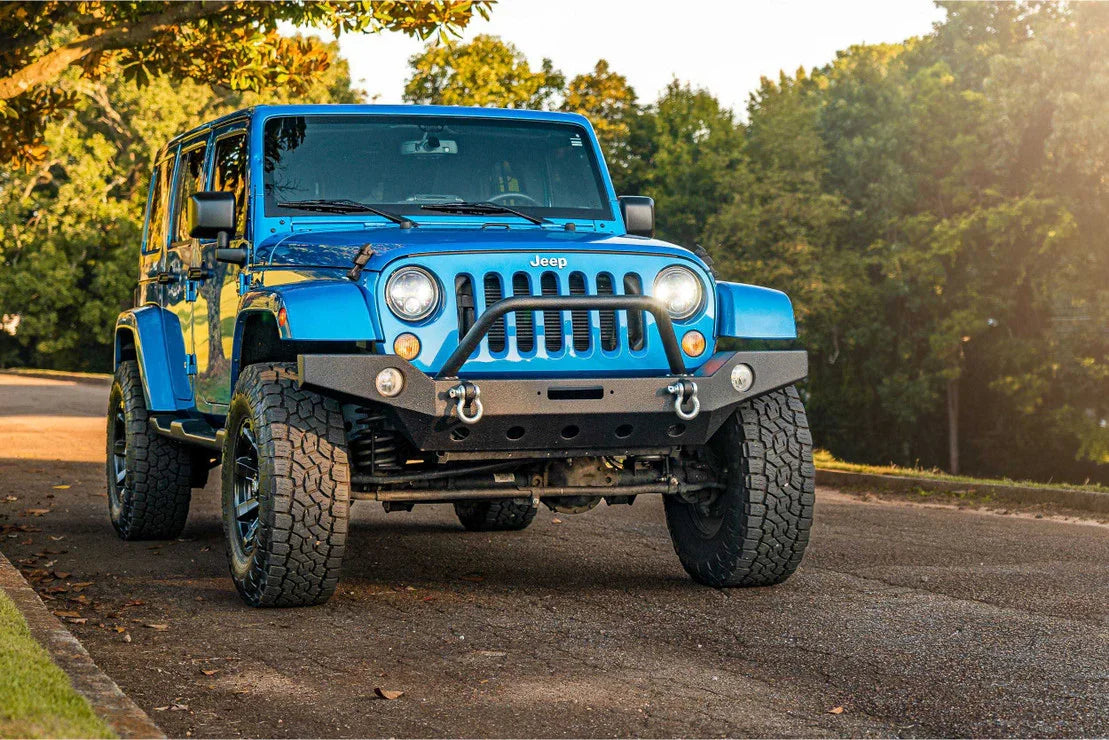 Blue Jeep Wrangler with off-road bumper and large tires parked outdoors