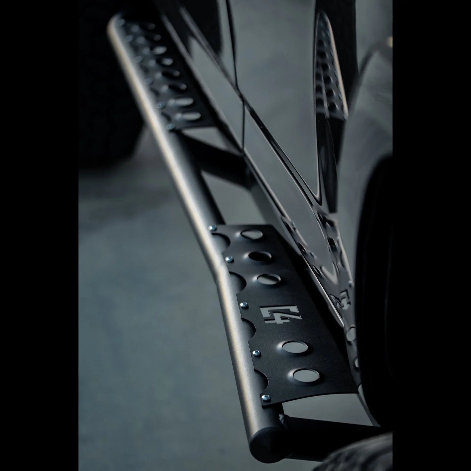 Close-up of Toyota 4Runner 5th Gen rock sliders, black steel with perforated step plate.