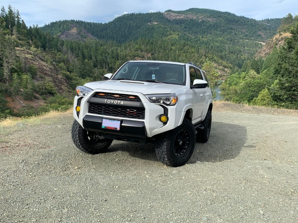Lifted white Toyota 4Runner SUV with off-road tires parked outdoors in a mountain landscape