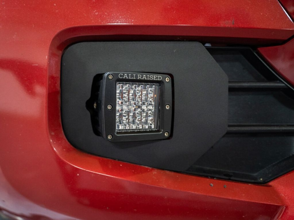 LED fog light pod installed on a red vehicle bumper for overlanding or off-road use