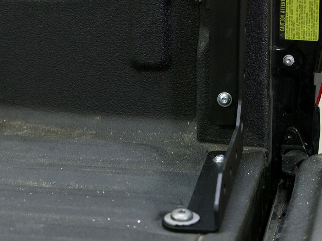 Close-up of a metal mounting bracket installed in a pickup truck bed, overlanding gear accessory