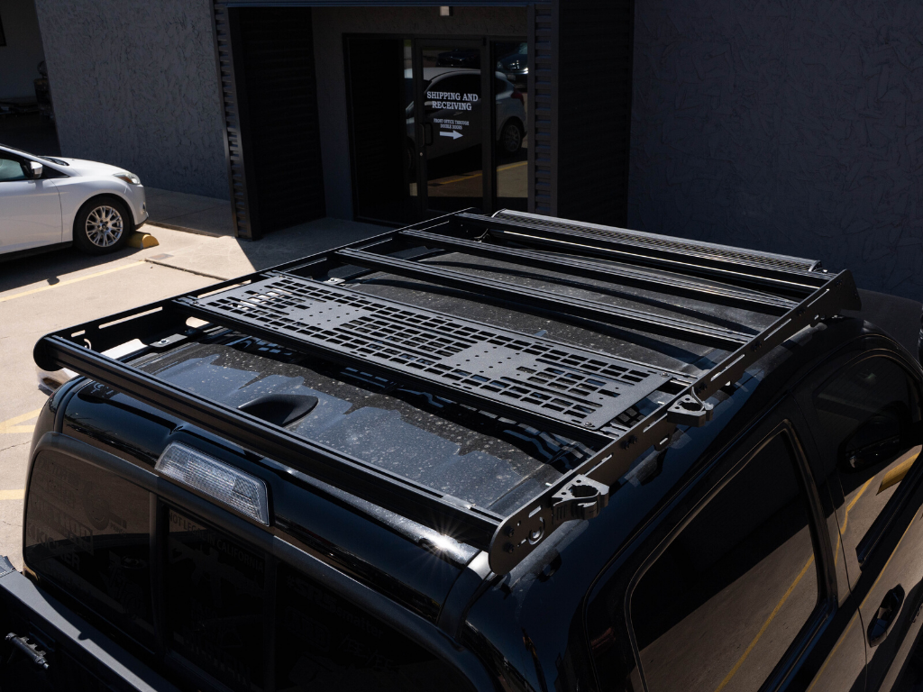 Heavy-duty roof rack system mounted on black Toyota Tacoma for overlanding and camping gear