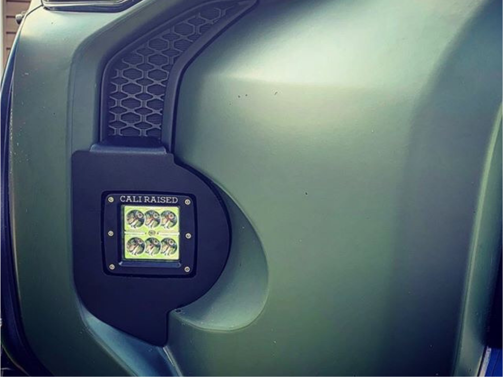 Cali Raised LED ditch light installed on a matte green Toyota truck fender close-up