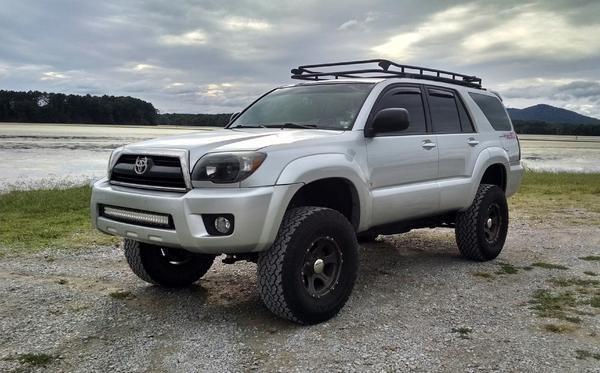 Lifted silver Toyota 4Runner with roof rack and off-road tires parked outdoors