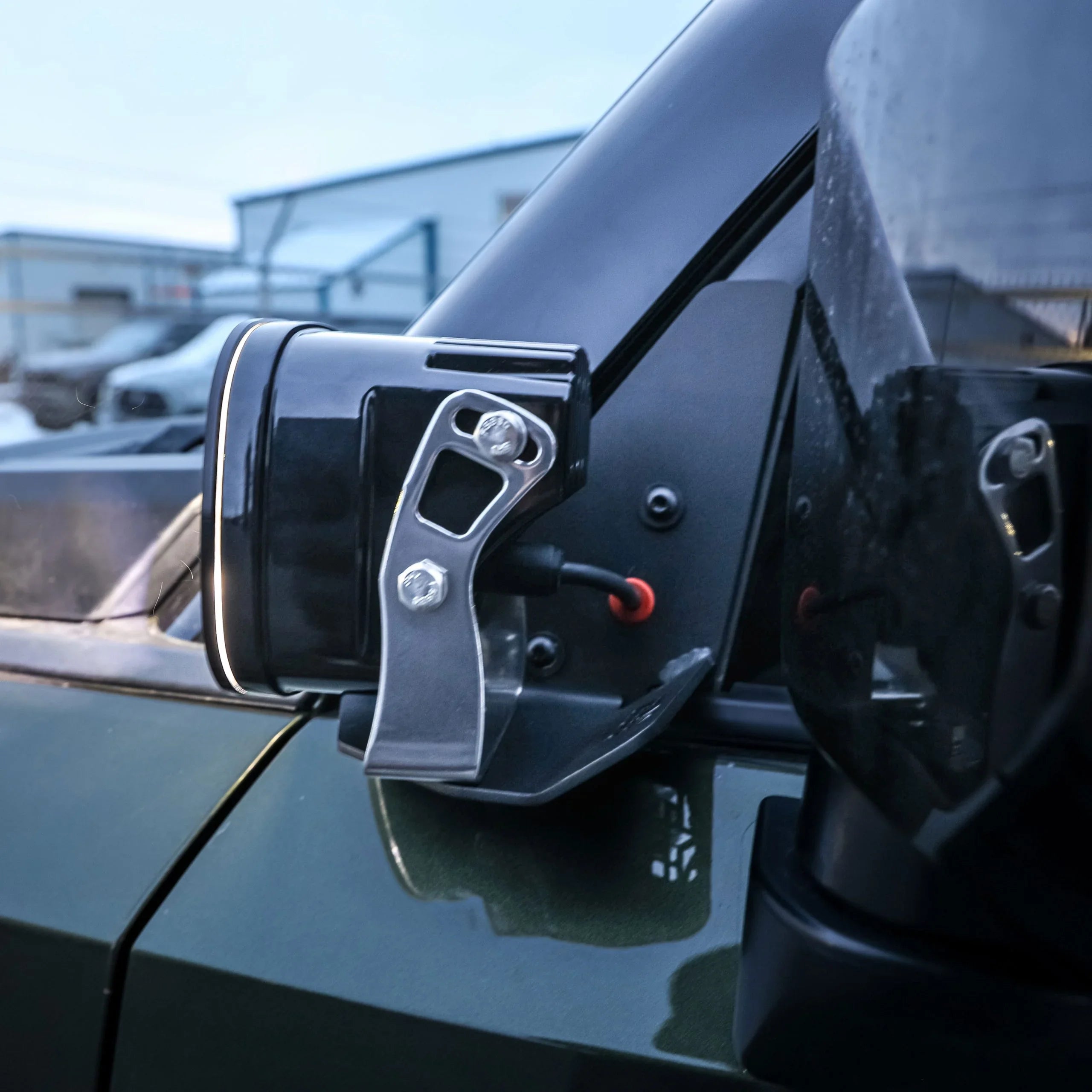 Close-up of off-road ditch light mounted on a vehicle, with rugged steel bracket hardware