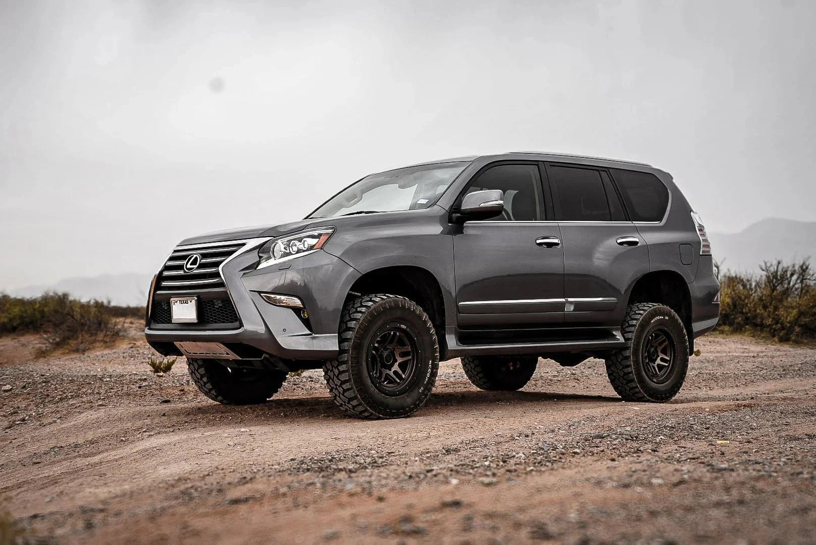 Lifted gray Lexus GX SUV with off-road tires parked on a rugged dirt trail outdoors