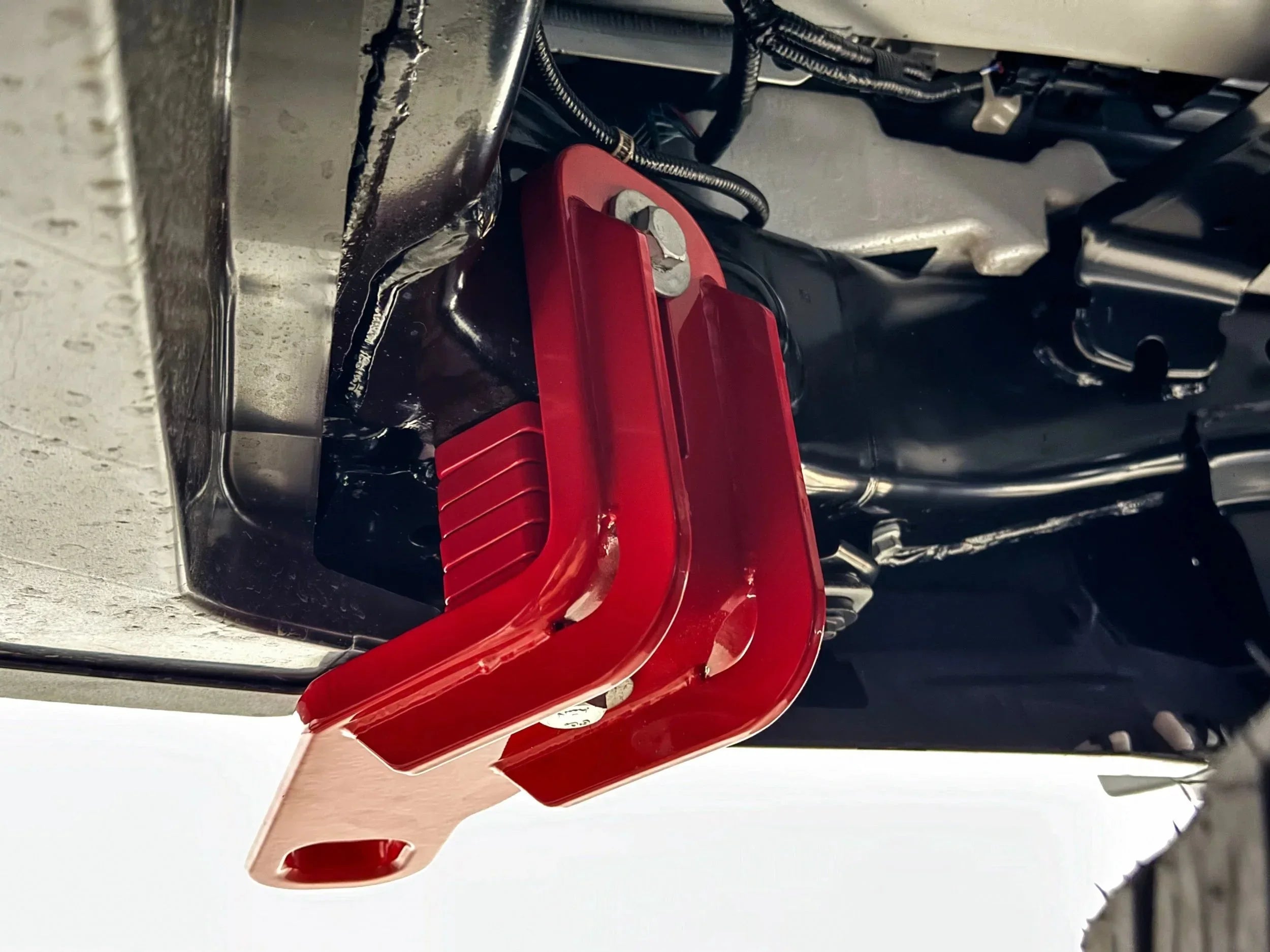 Red steel tow hook mounted under vehicle chassis for off-road recovery