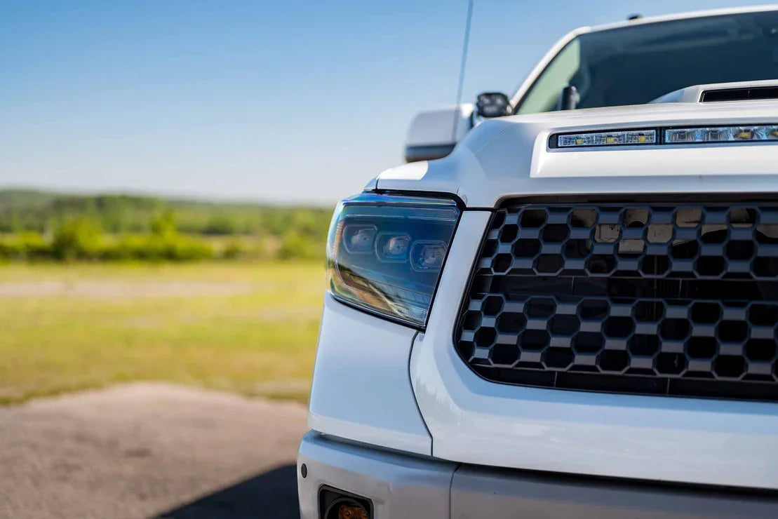 Close-up of white Toyota Tundra with aftermarket XB headlights and honeycomb grille outdoors