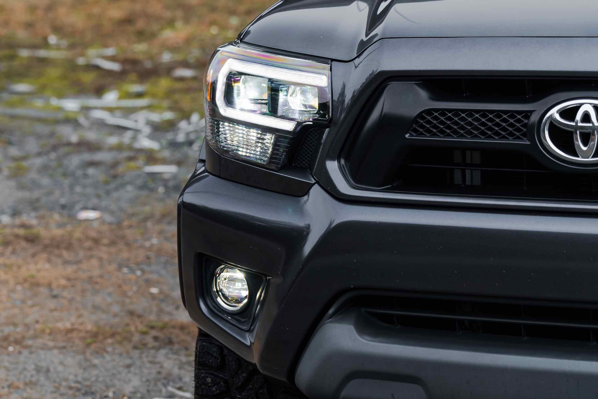 Close-up of Toyota Tacoma front grille with aftermarket hybrid LED headlights and fog light