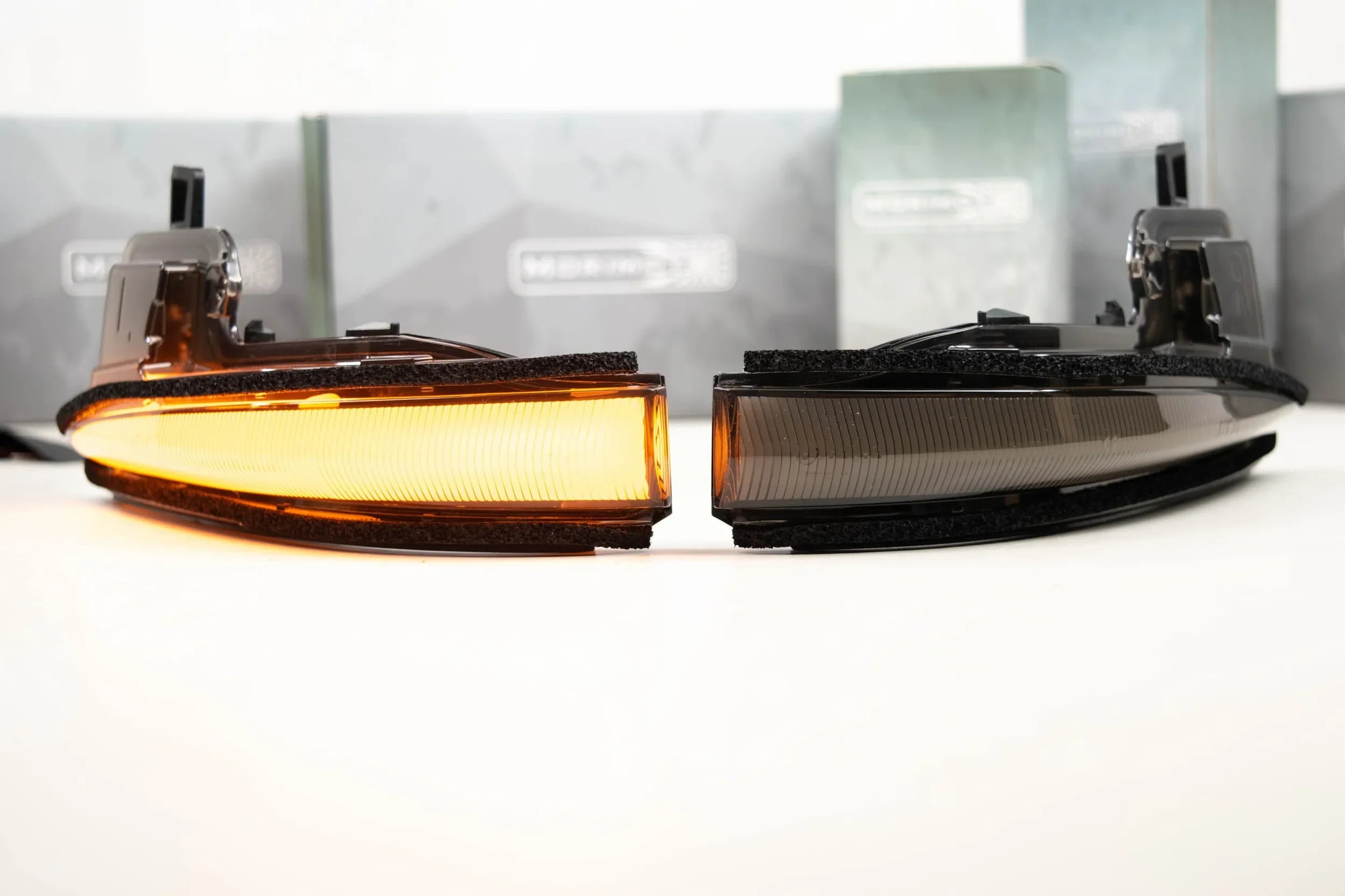Toyota Tacoma LED mirror turn signal lights, one illuminated amber, on white surface