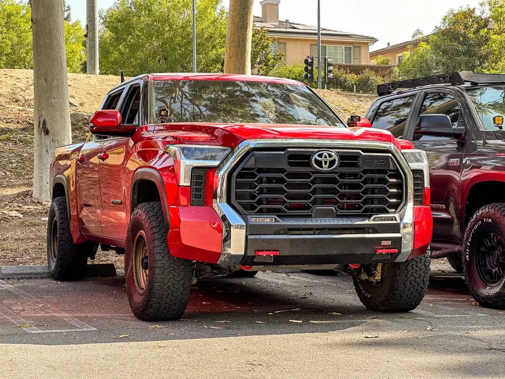 Red Toyota Tundra TRD Pro with off-road tires parked outdoors, suitable for overlanding gear.