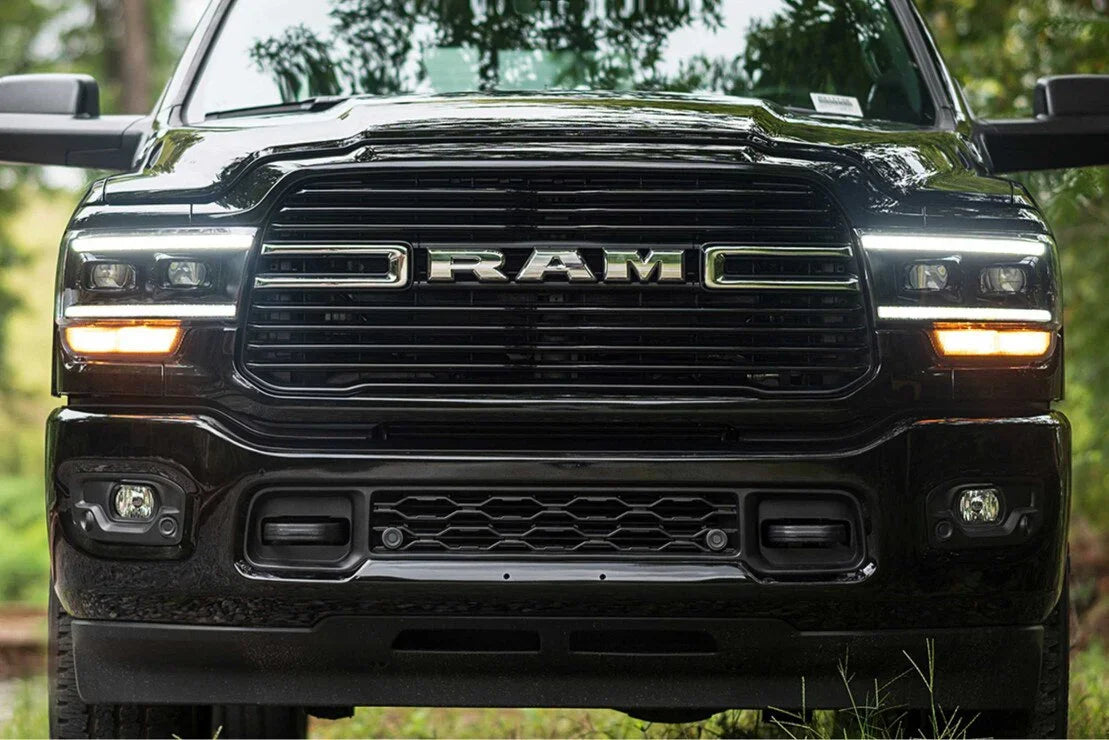 Front view of black RAM truck grille and headlights in outdoor setting