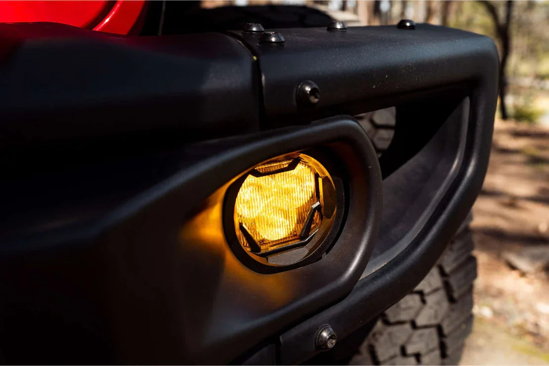 Close-up of off-road vehicle amber fog light in rugged black bumper outdoors
