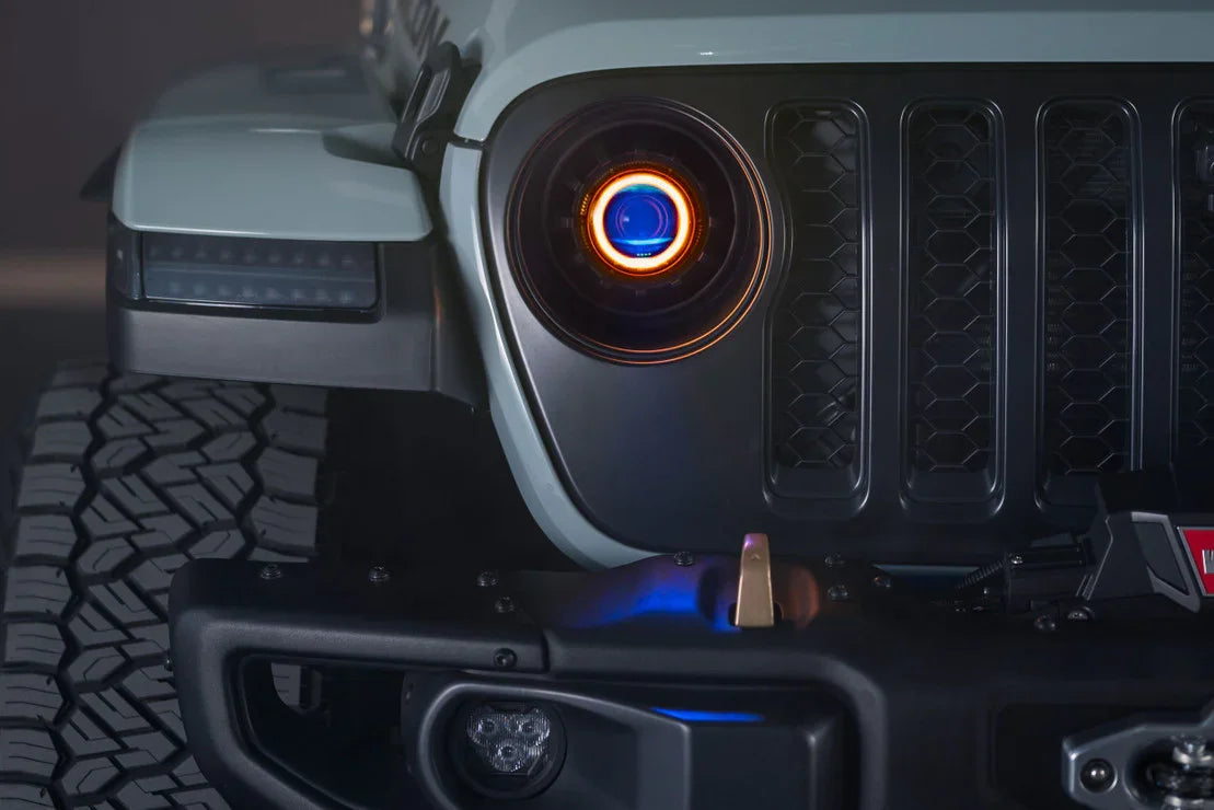 Close-up of Jeep Wrangler front grille, tire tread, LED headlight, and off-road bumper