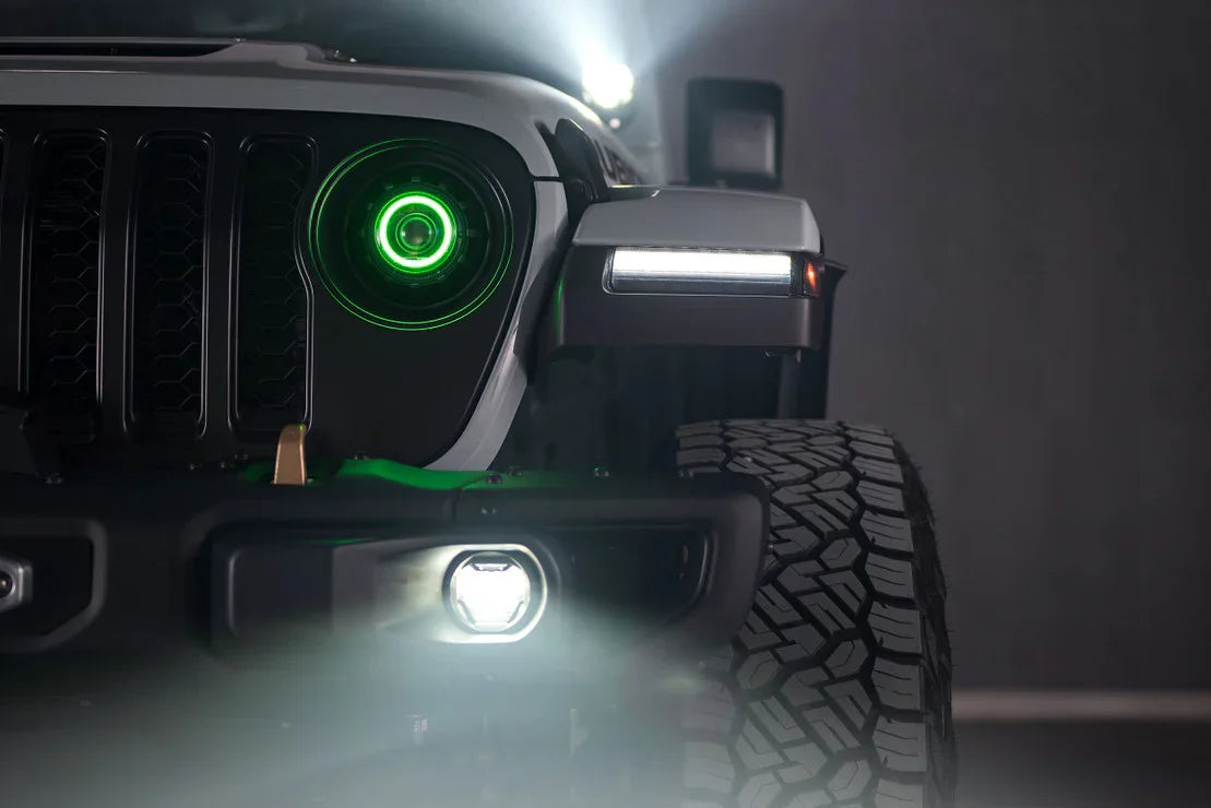 Close-up of Jeep front grille and tire, featuring green LED headlight and off-road accessory lighting