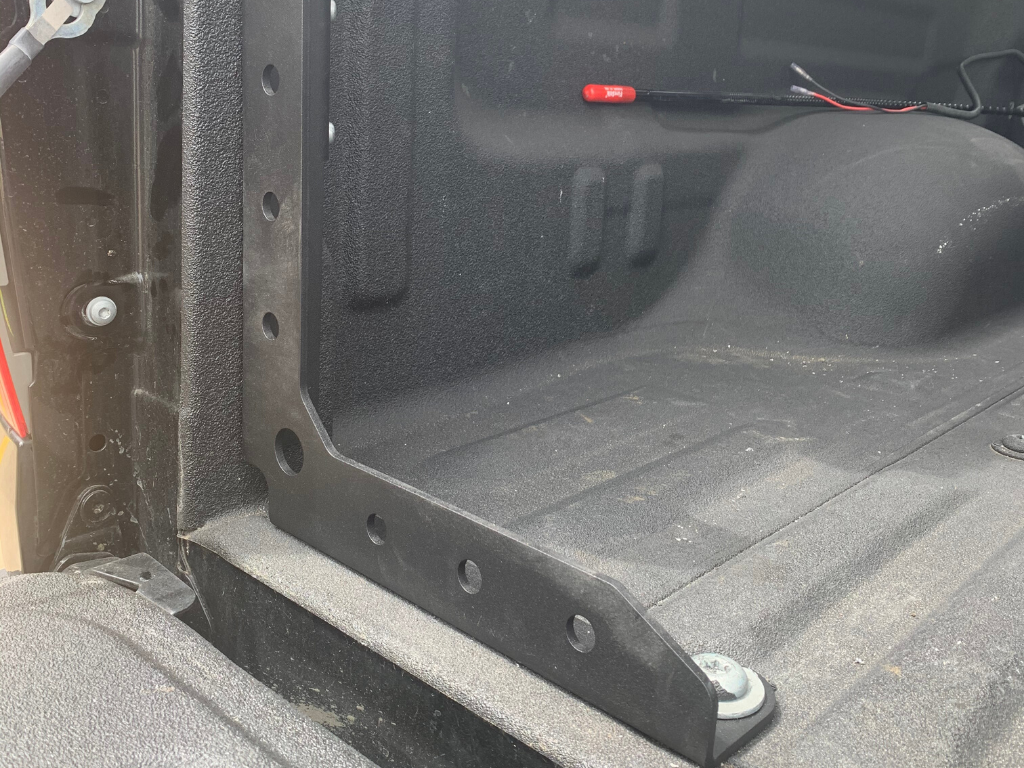 Closeup of truck bed with installed overland accessory mounting bracket and textured liner