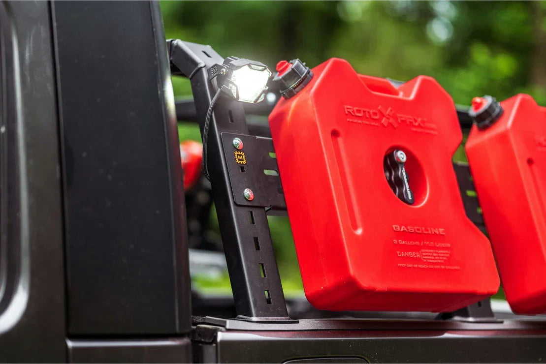 Off-road vehicle bed rack with red RotopaX gas canisters and mounted LED utility light
