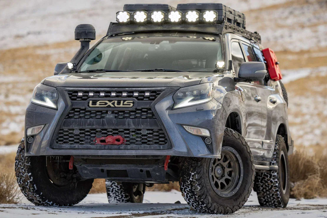 Lexus SUV equipped with overlanding gear, off-road tires, roof rack, and LED lights in snowy terrain