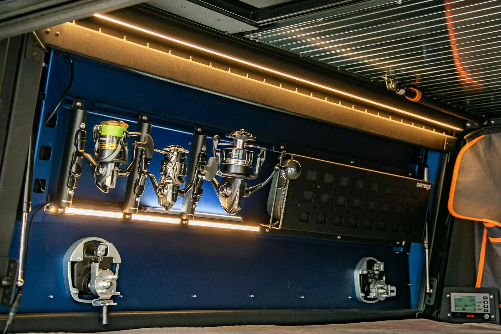 Overland vehicle camping storage panel with fishing reels, LED lights, and gear rack