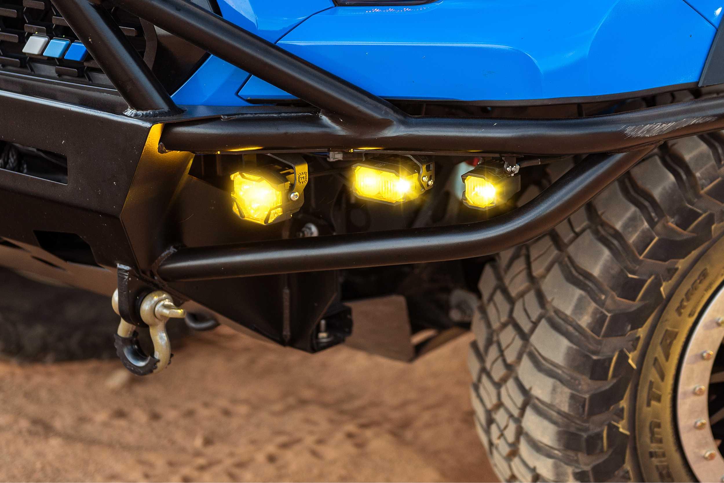 Off-road vehicle steel bumper with yellow LED lights and rugged tire on sandy terrain