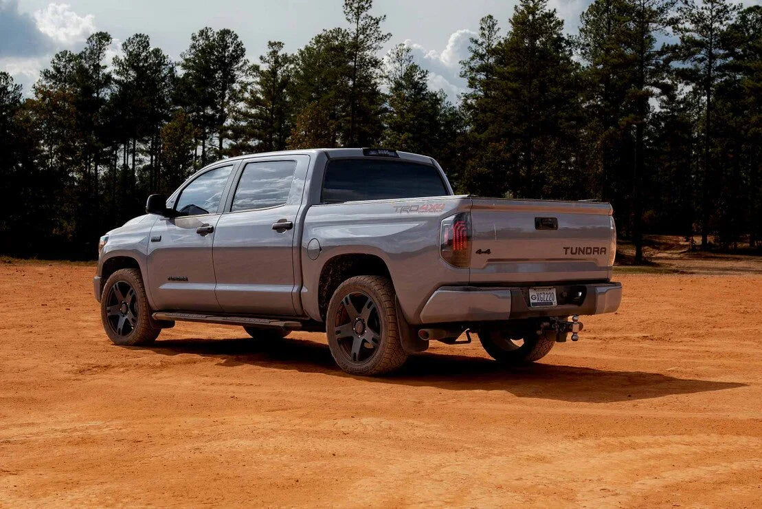 Silver Toyota Tundra TRD 4x4 pickup truck parked on dirt with pine trees in the background