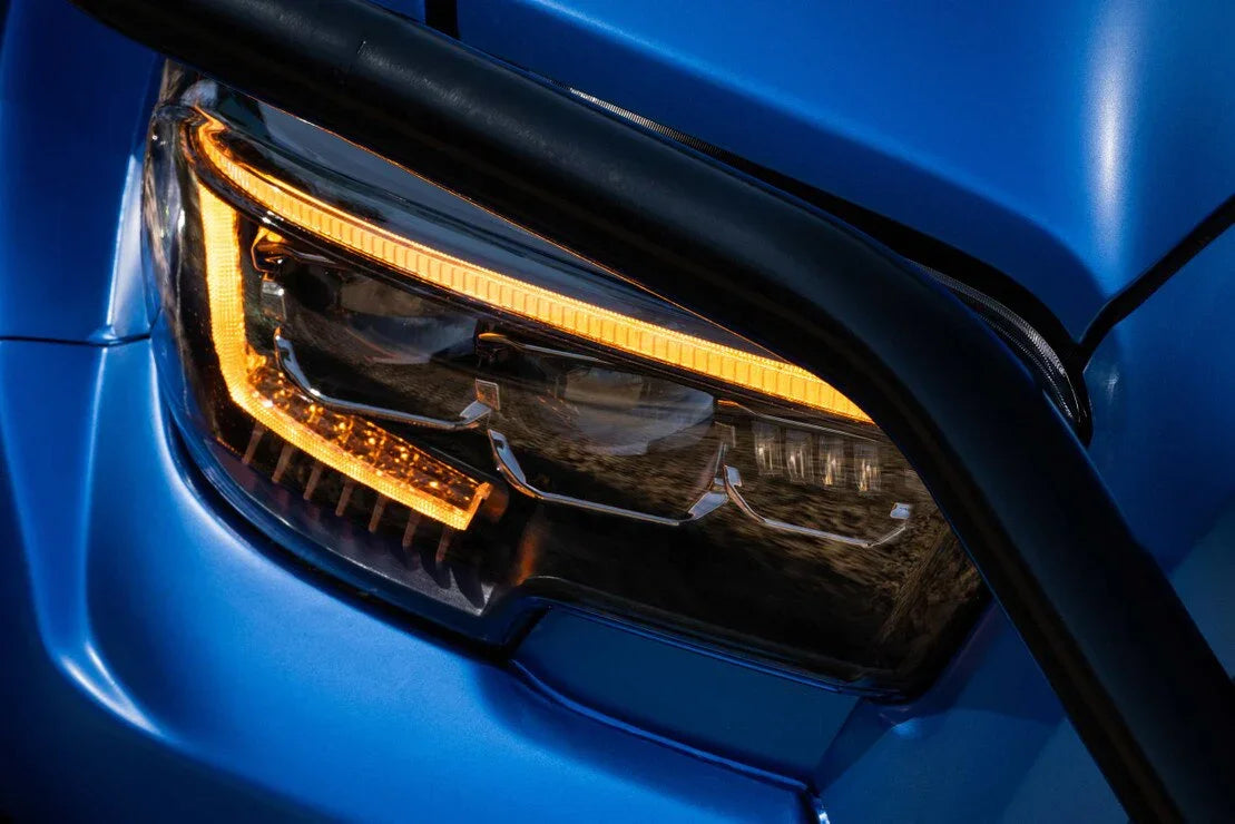 Close-up of a Toyota Tacoma XB Evo LED headlight on a blue vehicle with amber signal light.