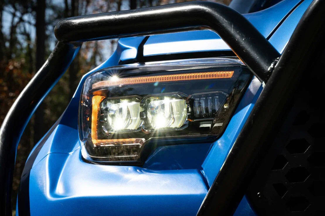 Close-up of LED Tacoma headlight on blue truck with protective grille, outdoors