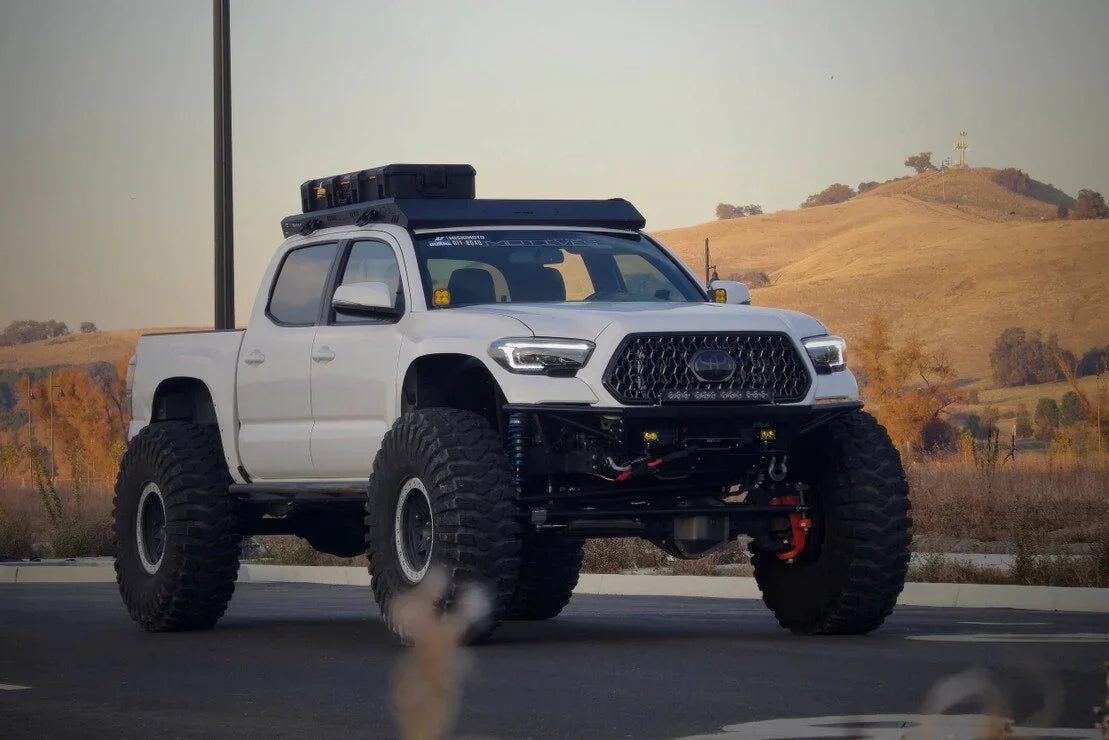 Lifted white Toyota Tacoma with XB Evo LED headlights, overland rack, off-road tires, outdoor setting