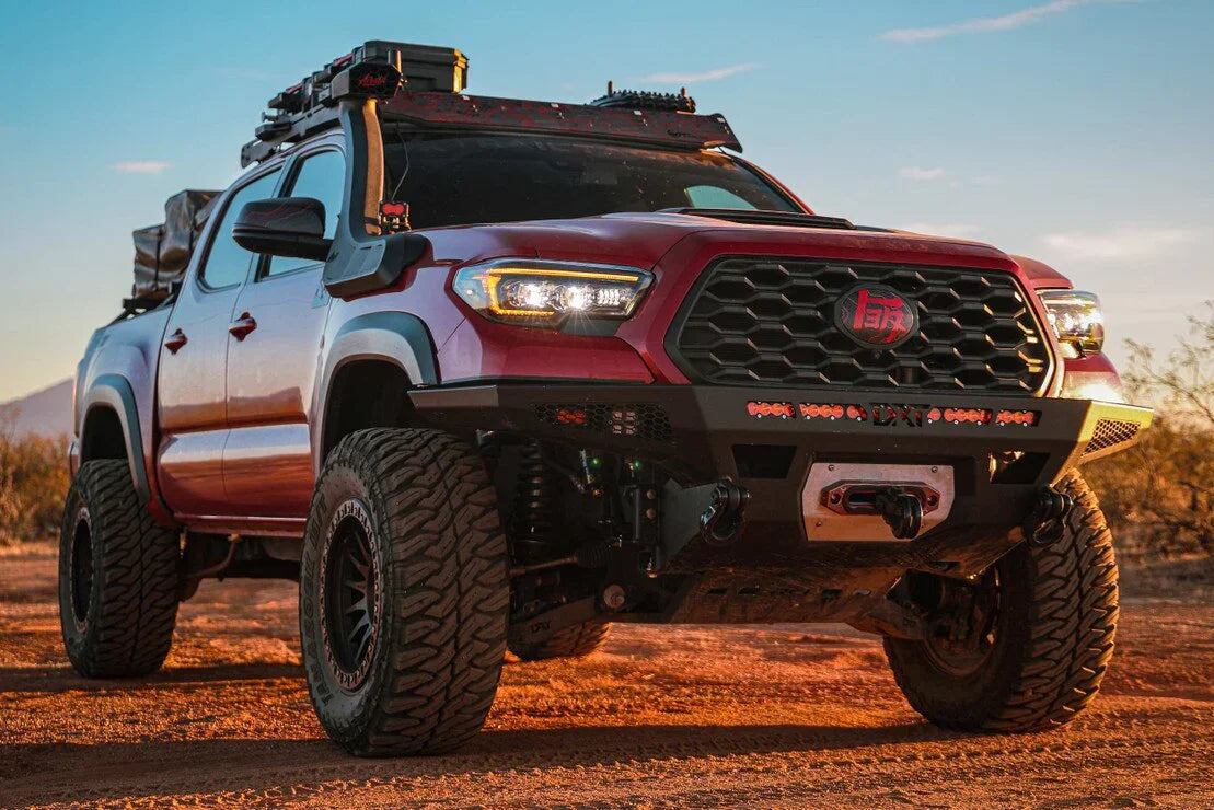 Lifted red Toyota Tacoma with off-road accessories and LED Evo headlights on a dirt trail