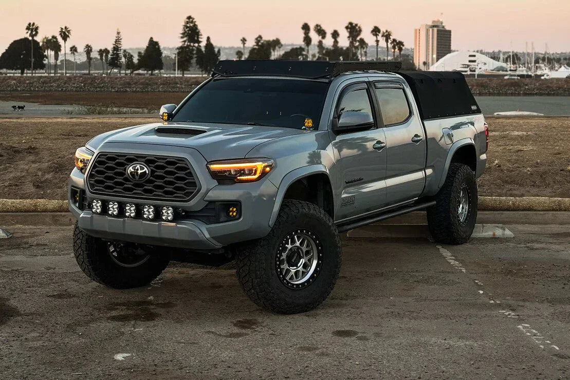 Toyota Tacoma with aftermarket XB Evo headlights and overlanding gear parked outdoors
