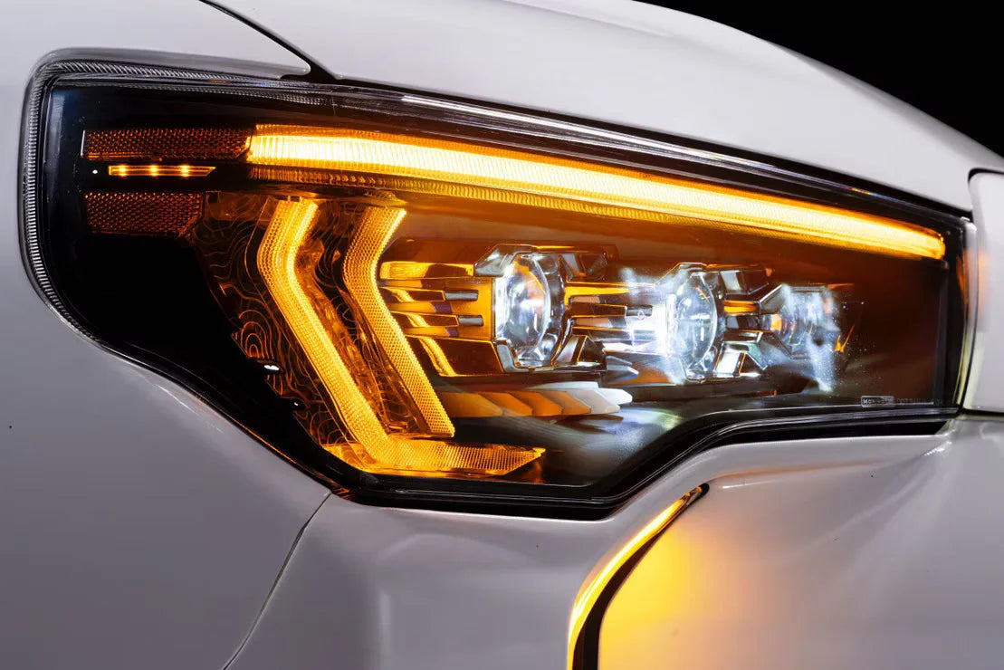 Close-up of LED headlight with amber accent on white Toyota Tacoma, overland vehicle accessory
