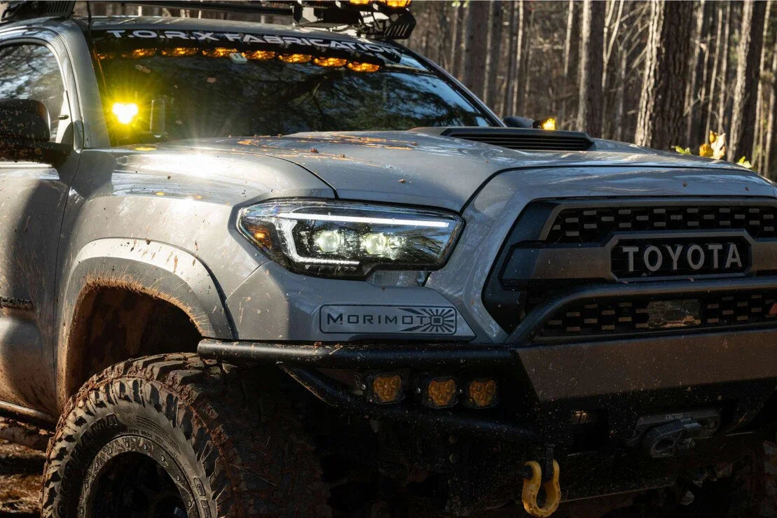 Toyota Tacoma with XB Evo Hybrid headlights and off-road accessories in a muddy forest